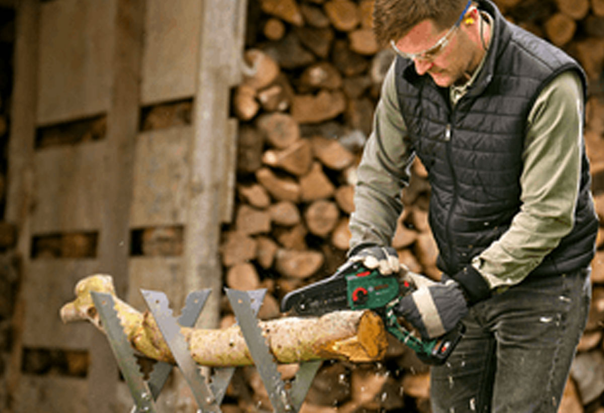Ένας άντρας κόβει ένα κορμό ξύλου.